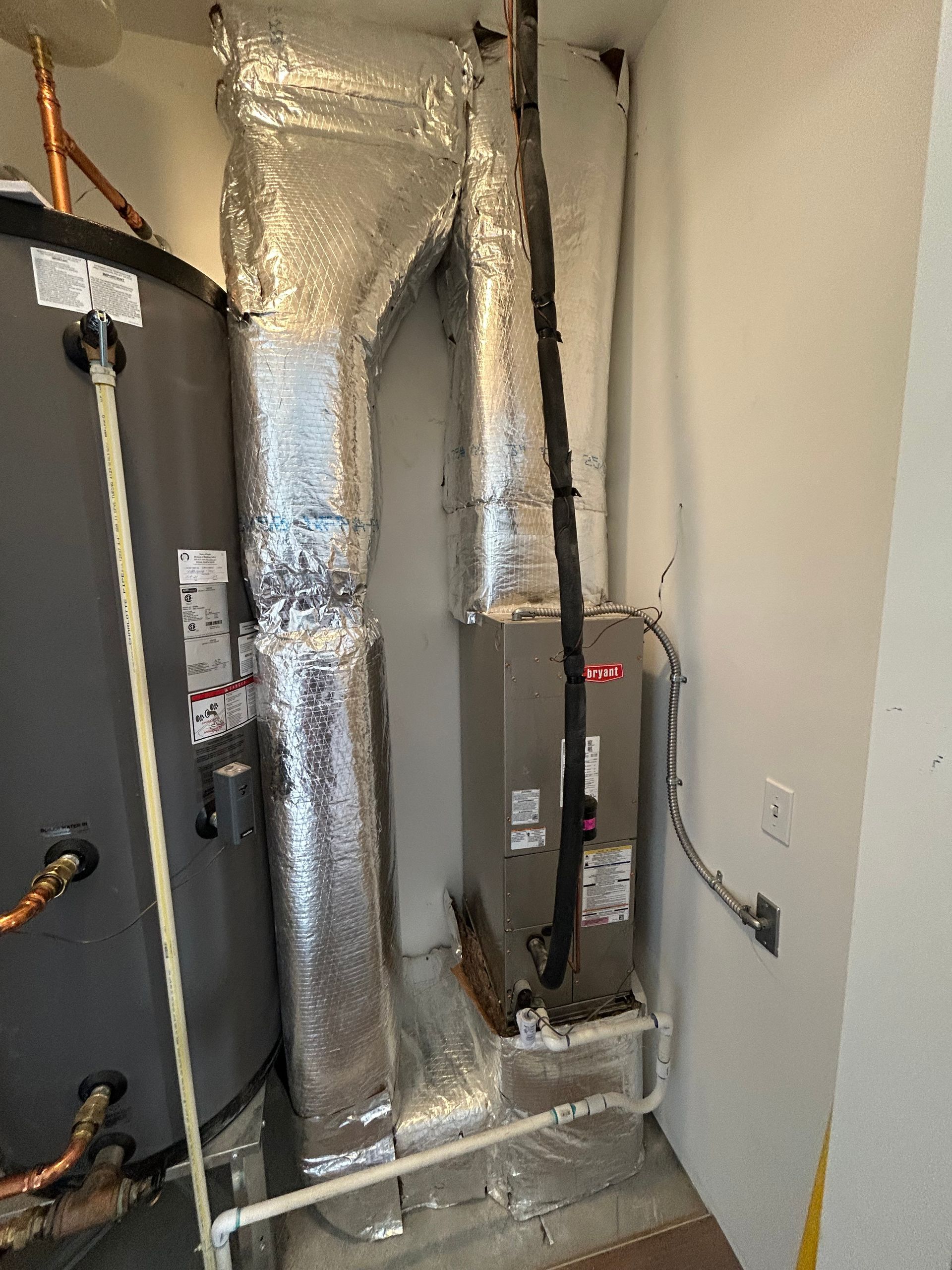 HVAC system with ductwork, water heater, and piping in an indoor utility closet.
