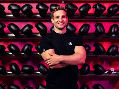 Fitness professional standing in front of a shelves full of boxing gloves