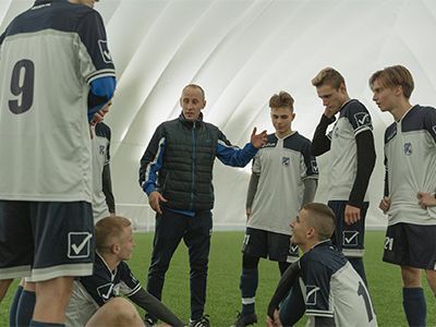 A group of soccer players are talking to their coach on the field.