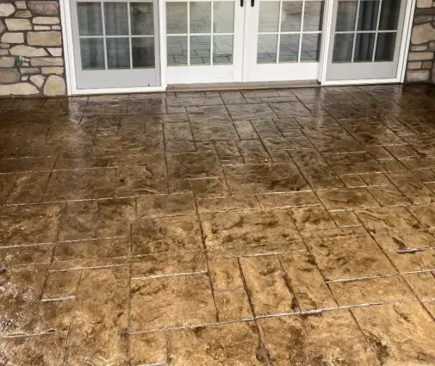 A concrete patio with a stone wall and sliding glass doors.