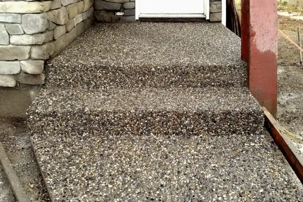 A set of stairs leading up to a door with a stone wall in the background.