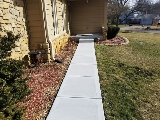 A concrete walkway leading to the front door of a house.