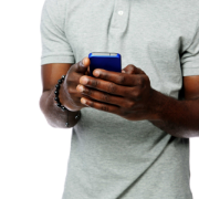 A man in a grey shirt is holding a cell phone in his hands