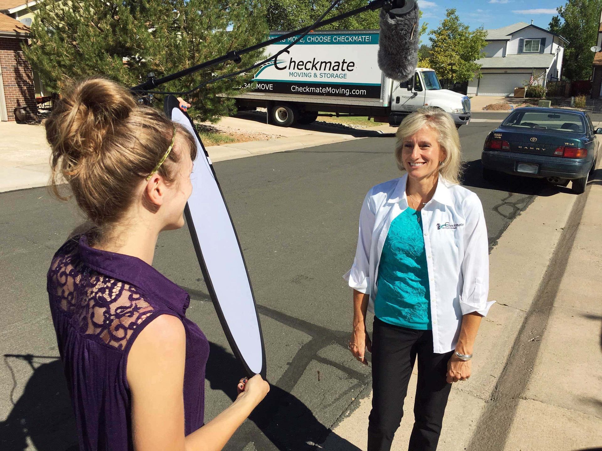 A woman talking to another woman in front of a checkmate truck