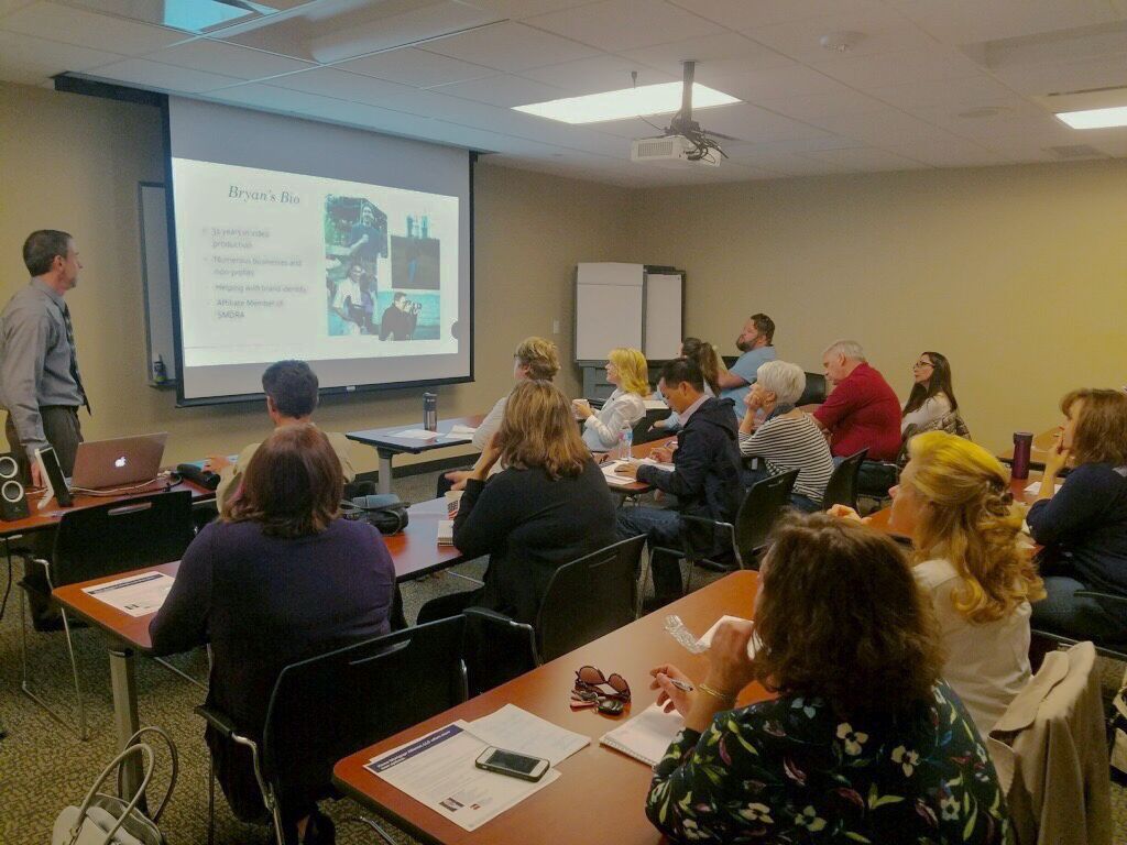 A man is giving a presentation to a group of people in a classroom.