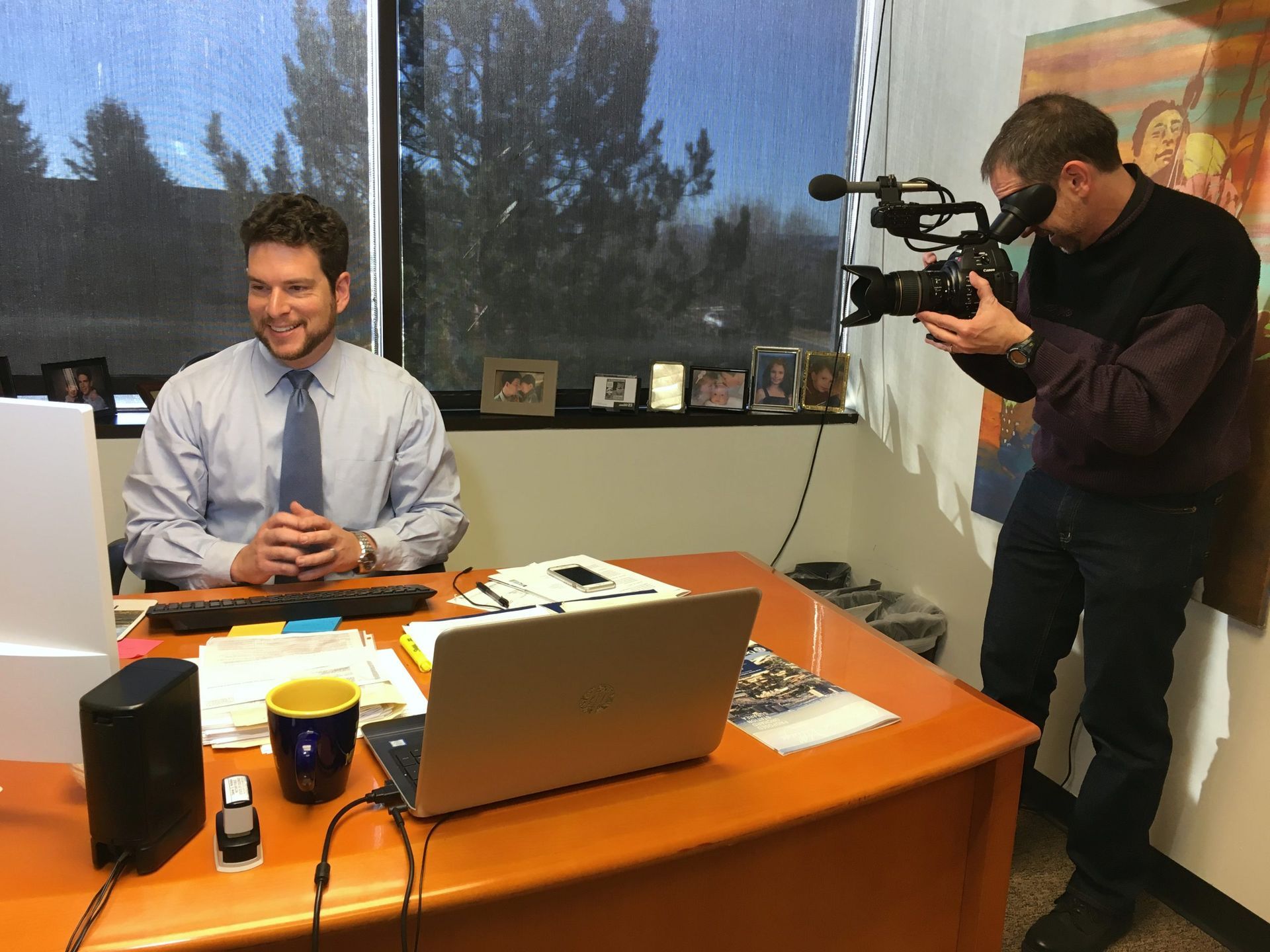 A man sitting at a desk with a laptop and a camera