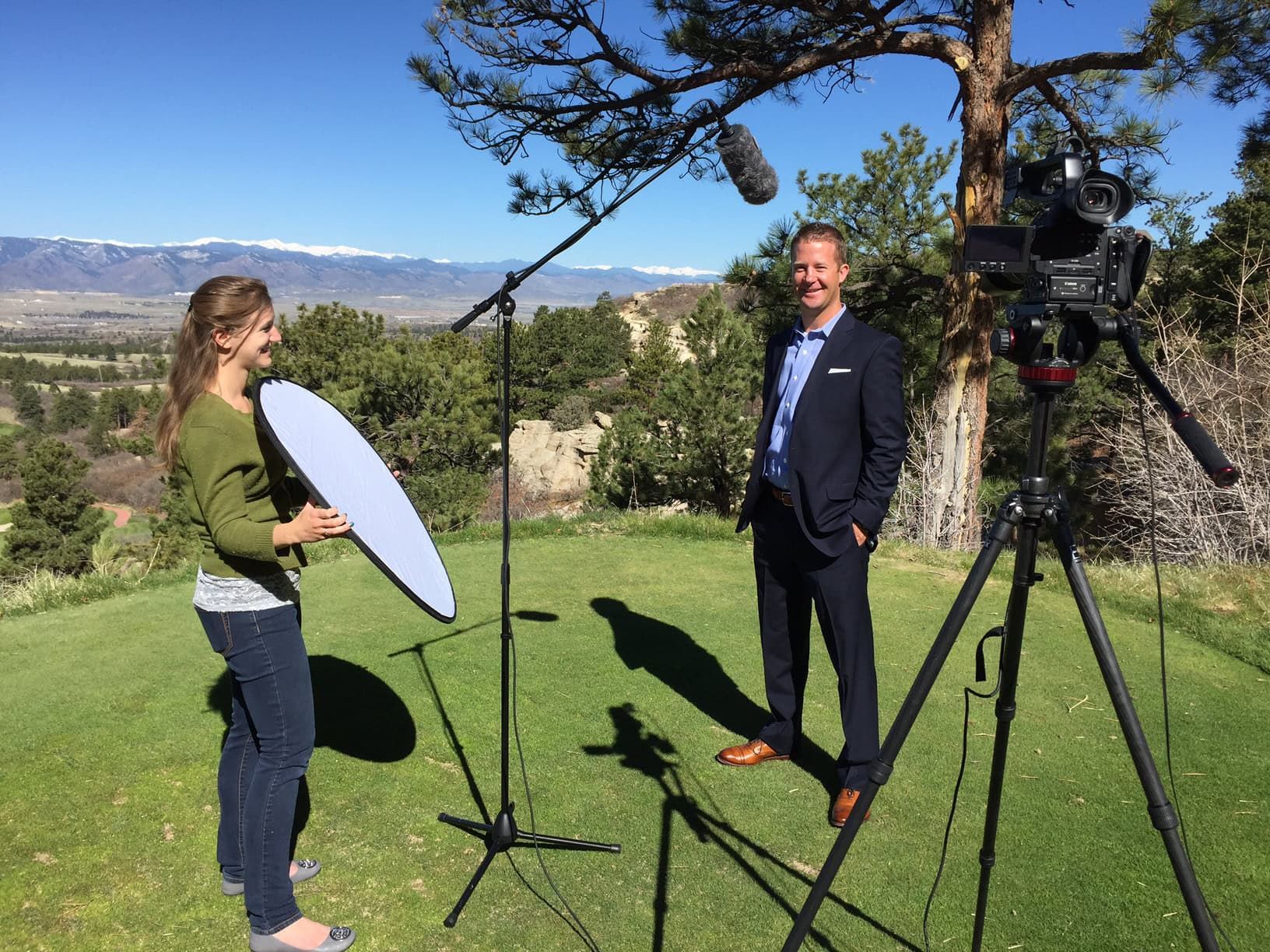 A man in a suit is being interviewed by a woman in front of a camera.