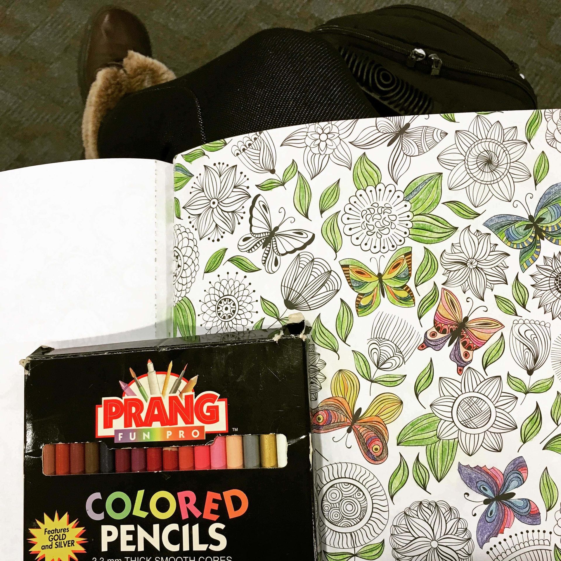 A box of prang colored pencils sits next to a coloring book