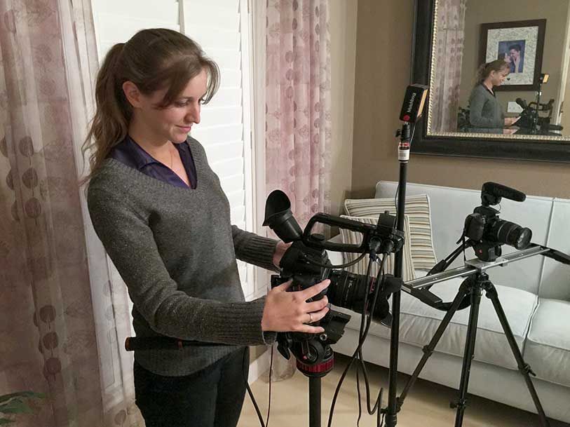 A woman is holding a camera in a living room