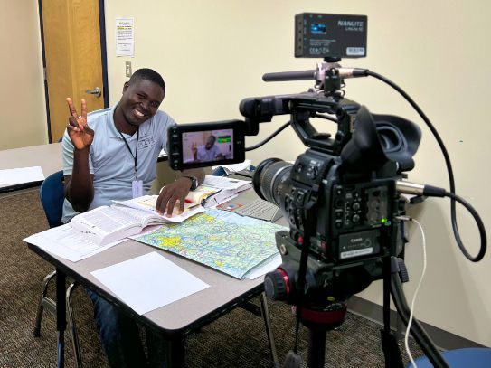 A man sitting at a table in front of a camera