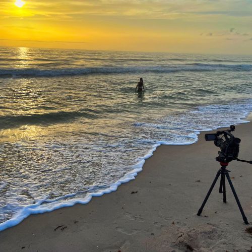 A camera is sitting on a tripod on a beach.
