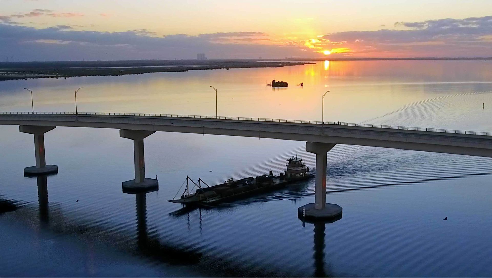 An aerial view of a bridge over a body of water at sunset.