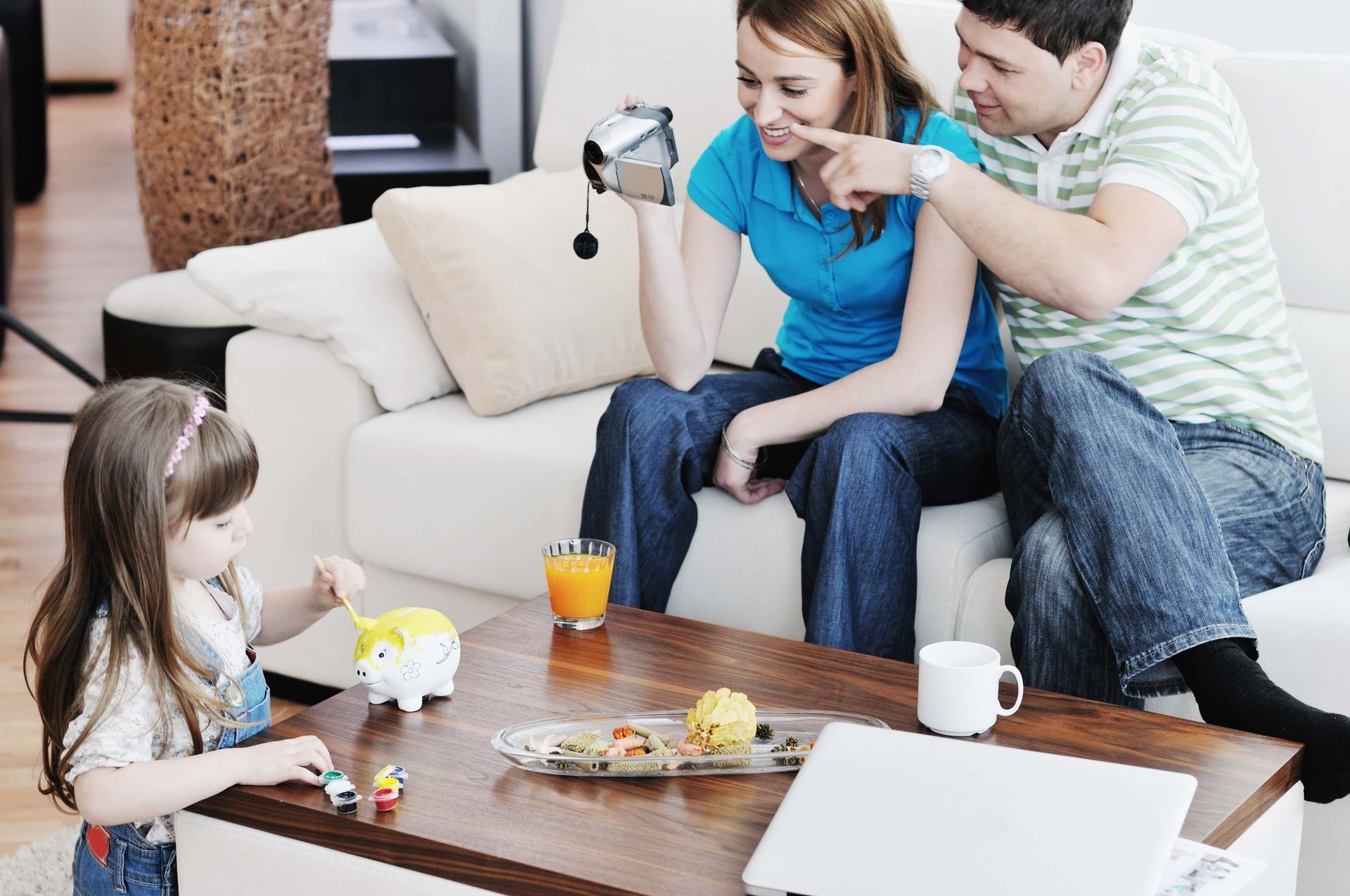 A family is sitting on a couch playing with a piggy bank