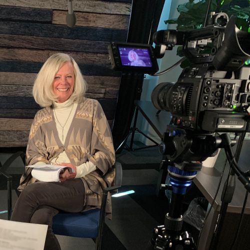 A woman is sitting in front of a camera and smiling