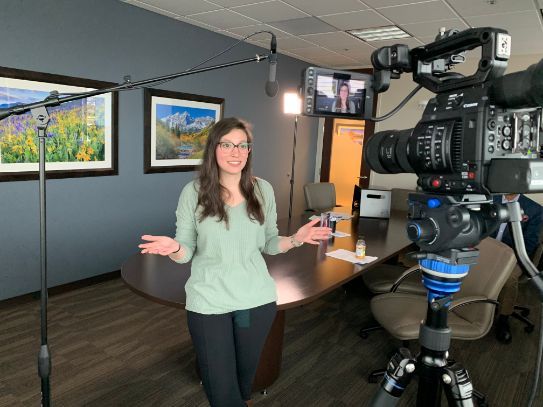 A woman is standing in front of a camera in a conference room.