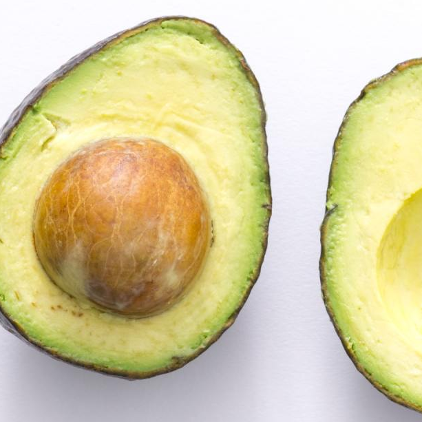 Two halves of an avocado on a white surface
