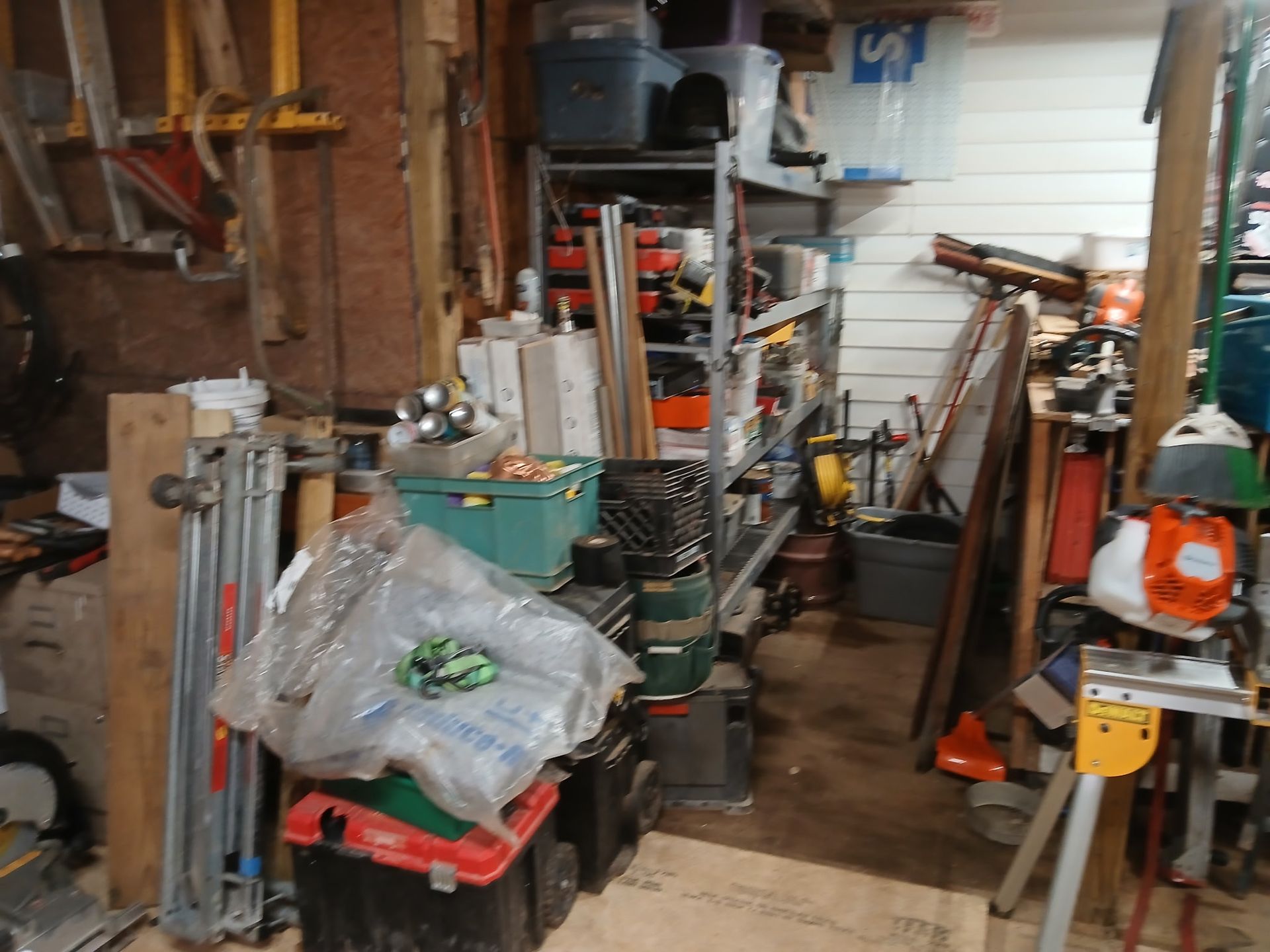 Cluttered garage interior with tools, shelves, and various items.