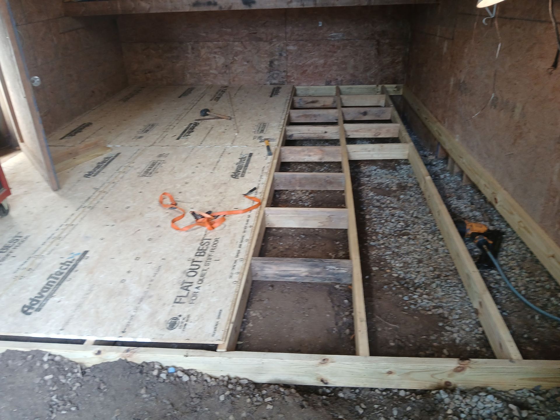 Construction of a wood floor with a frame. Plywood sheets and support beams in a dirt-floored space.