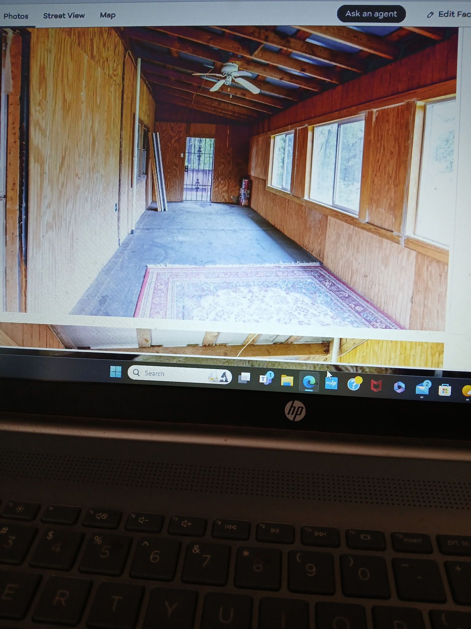 Long, narrow room with wood paneling, windows, and a rug.