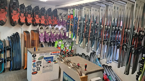 Fishing tackle shop wall lined with rods, reels, lures, and hanging gear