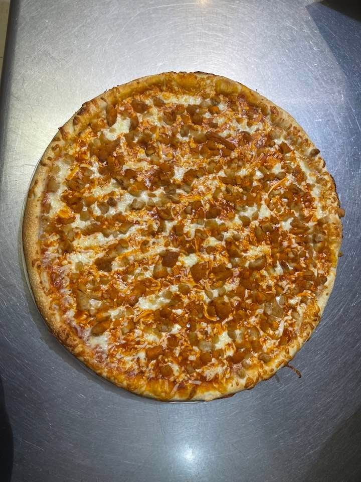 A buffalo chicken pizza is sitting on a table.