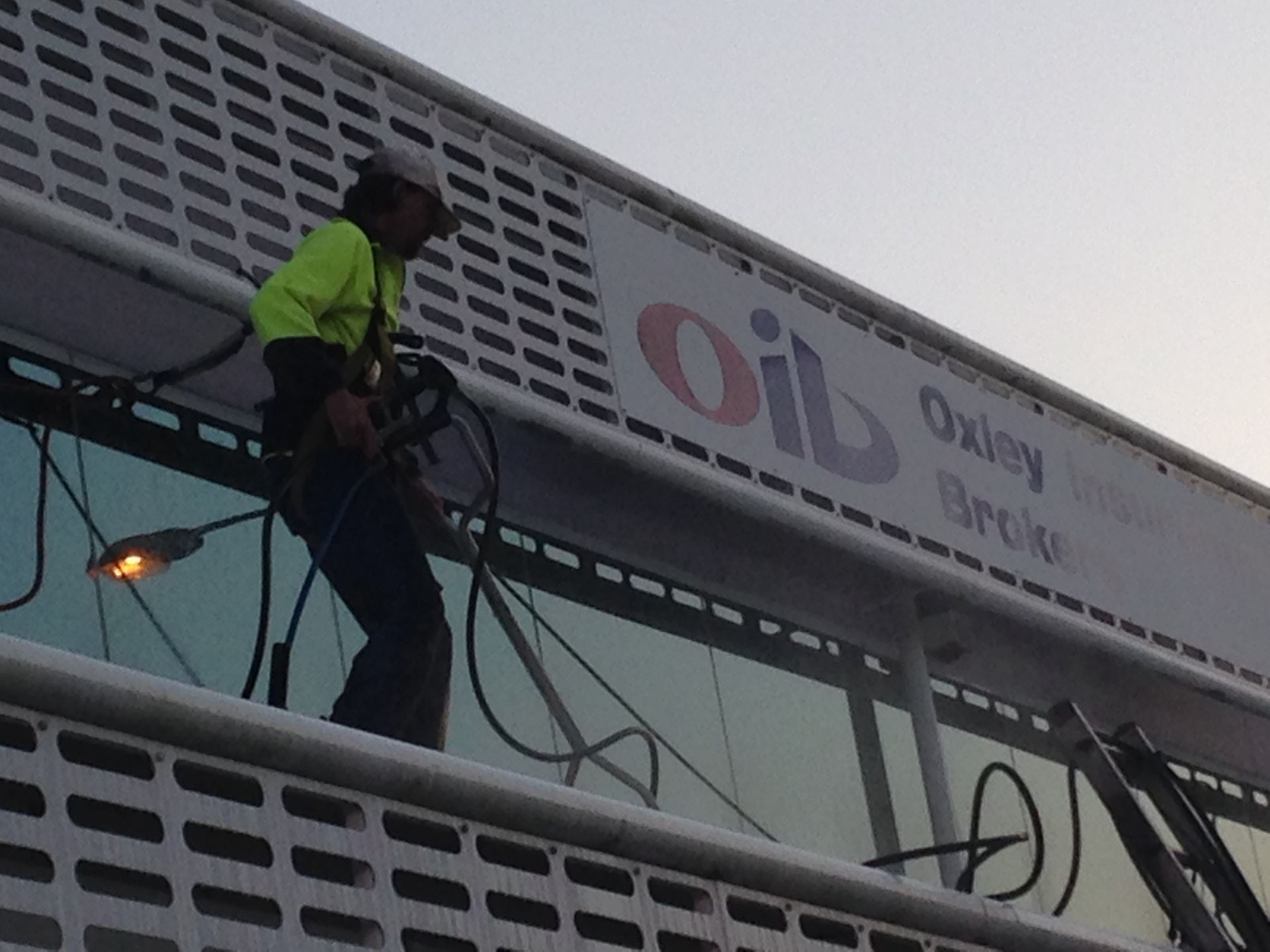 Worker In Safety Gear On Building Facade, Cleaning Windows Near 