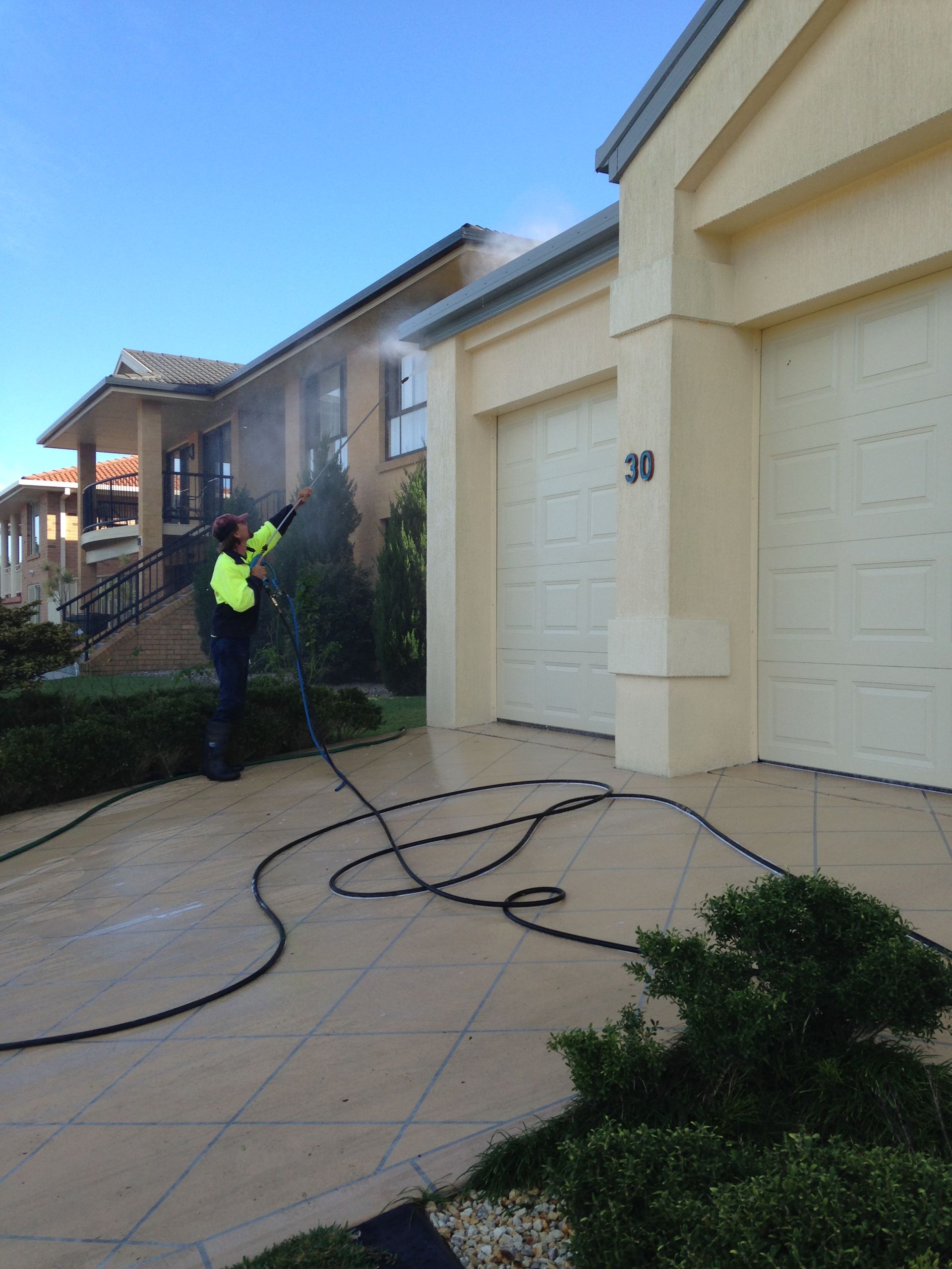 Cleaner Doing Pressure Cleaning Outside the House