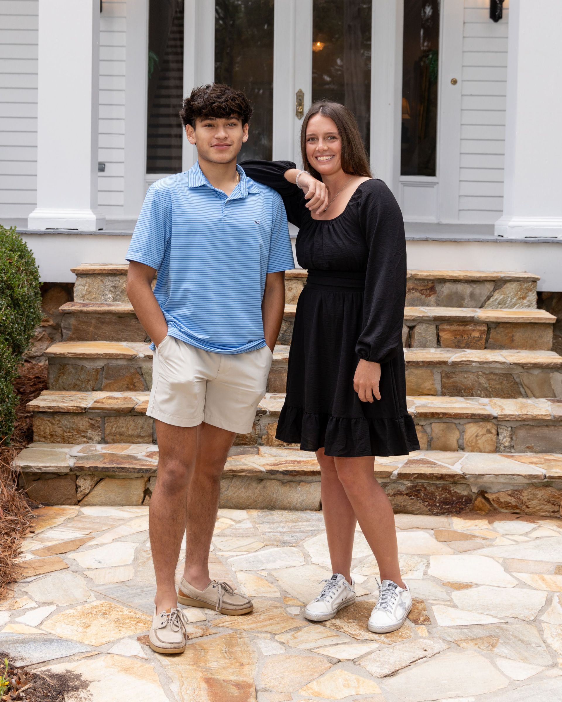 A man and a woman are standing next to each other in front of a house.