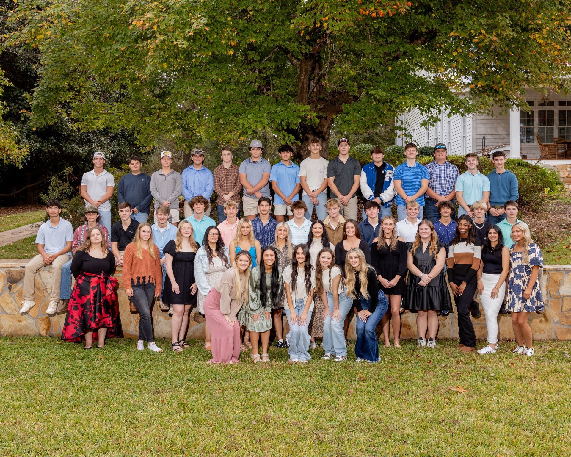 A large group of people are posing for a picture in front of a tree.