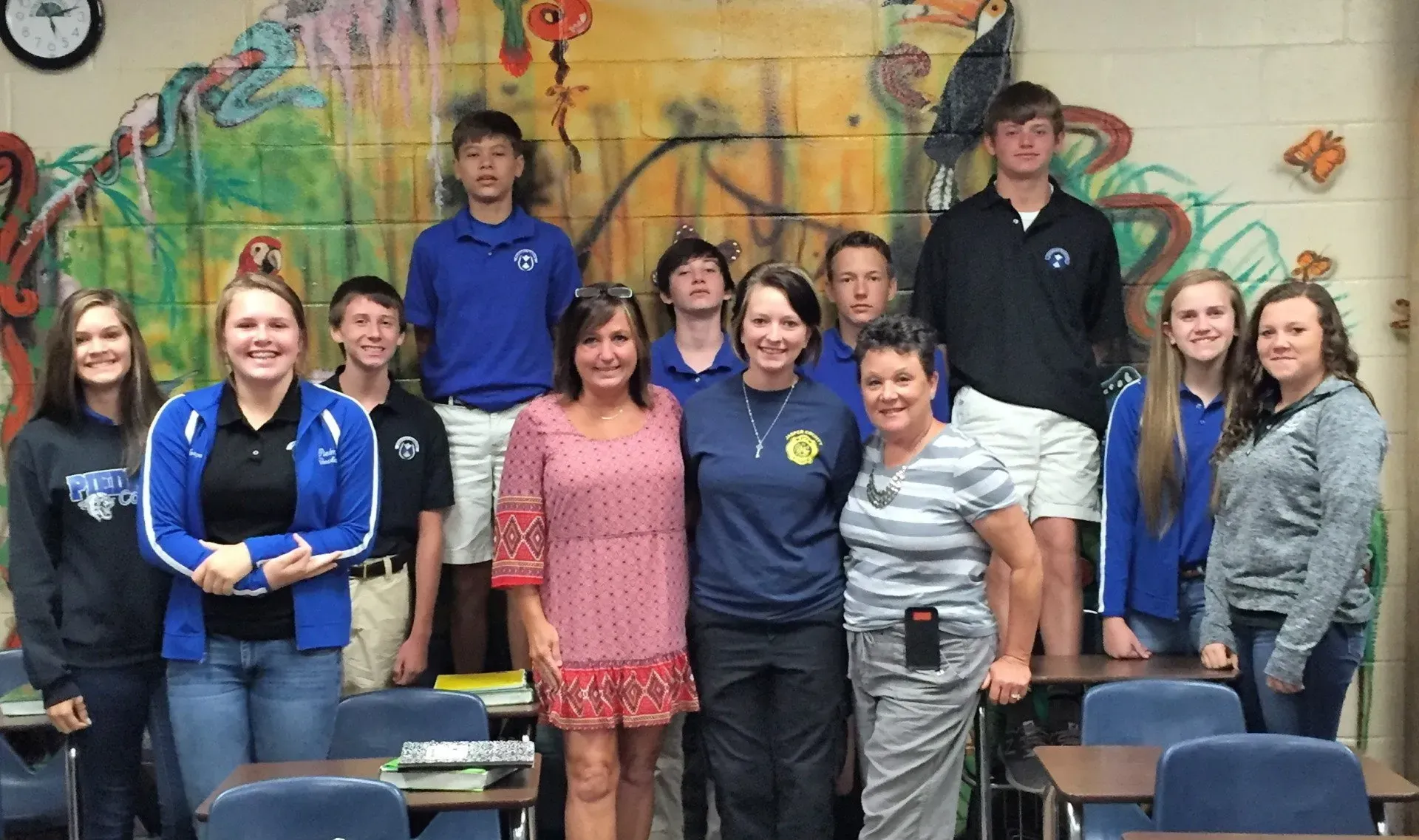 A group of people are posing for a picture in a classroom.