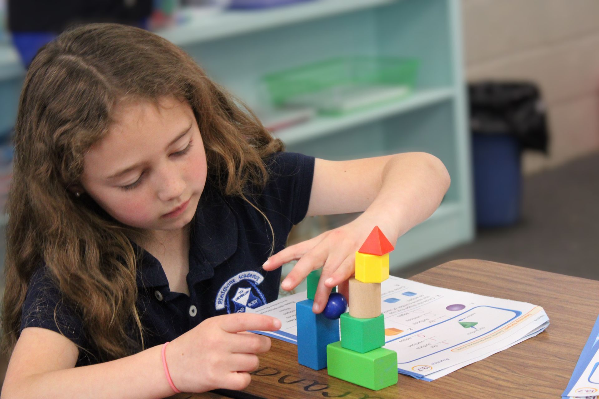 A group of young girls are making a gingerbread house in a classroom.