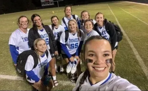 A group of girls are posing for a picture on a field.