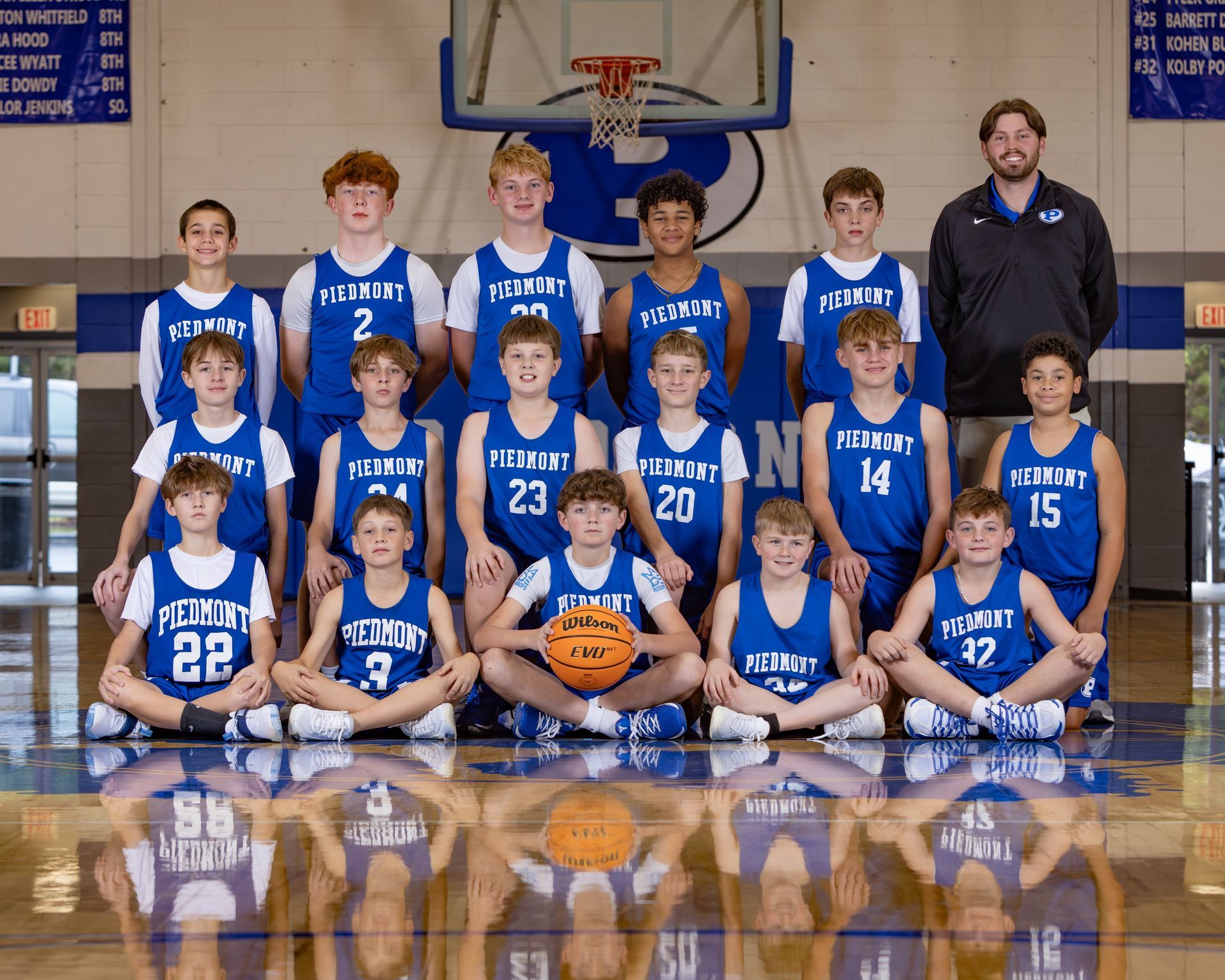 A basketball team is posing for a picture in front of a scoreboard.