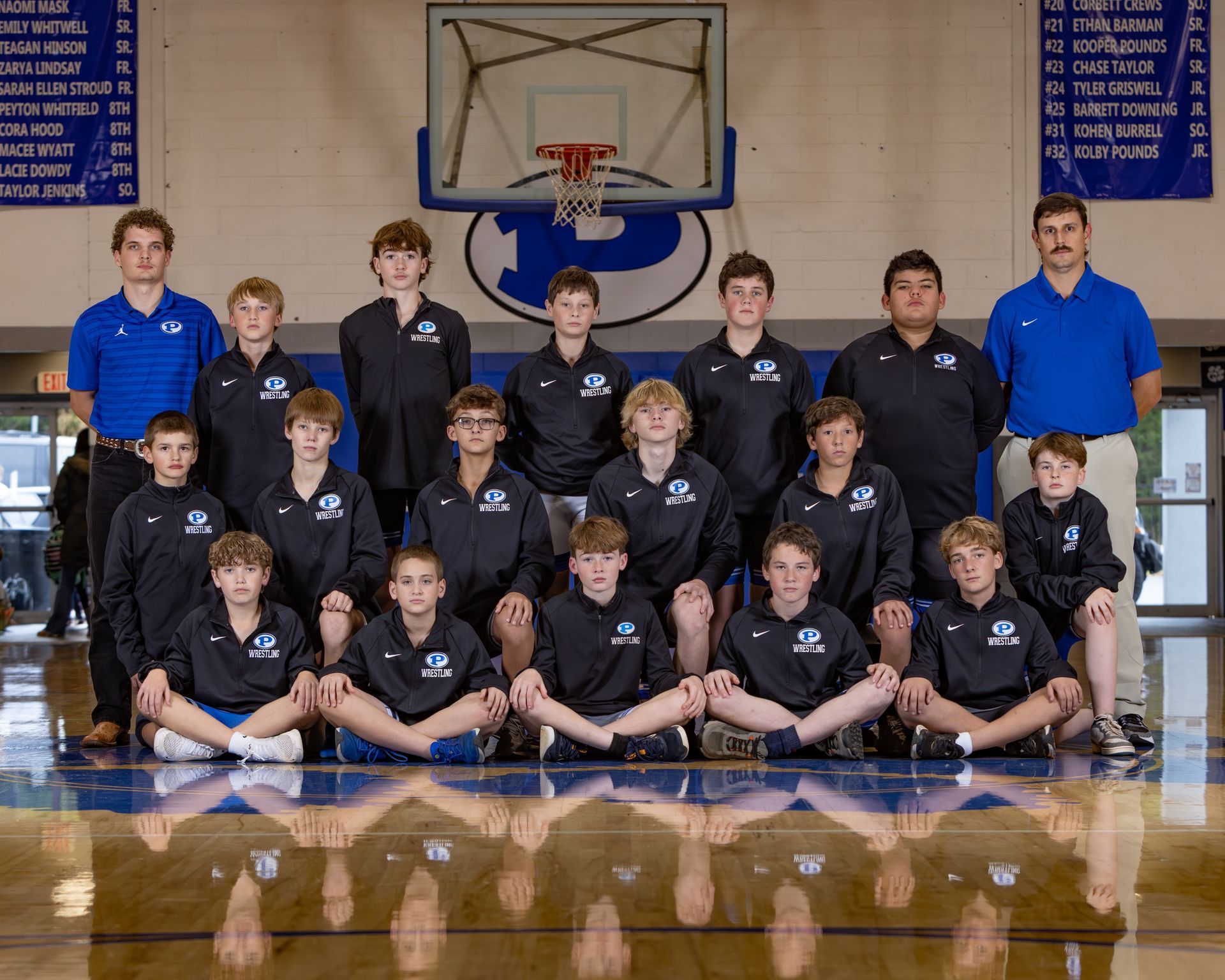 The cougars wrestling team is posing for a picture in front of a scoreboard.