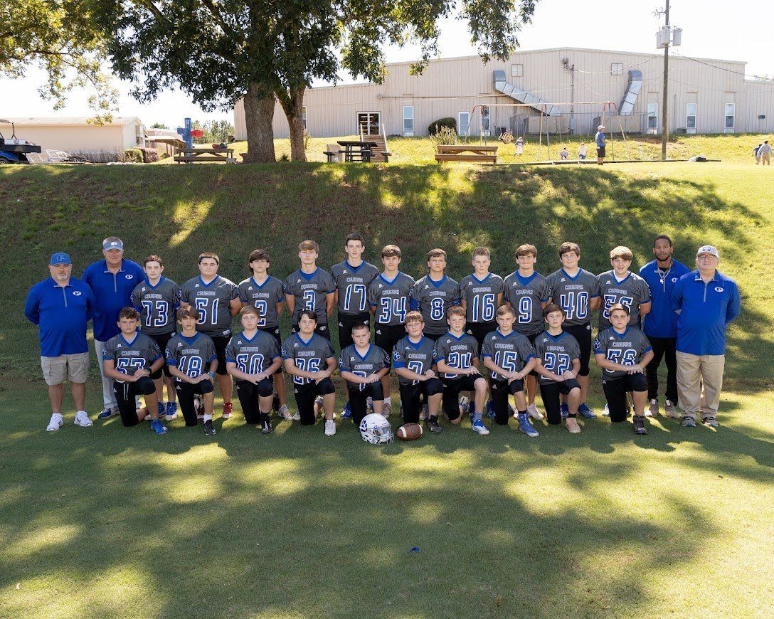 A football team is posing for a team photo on a field.