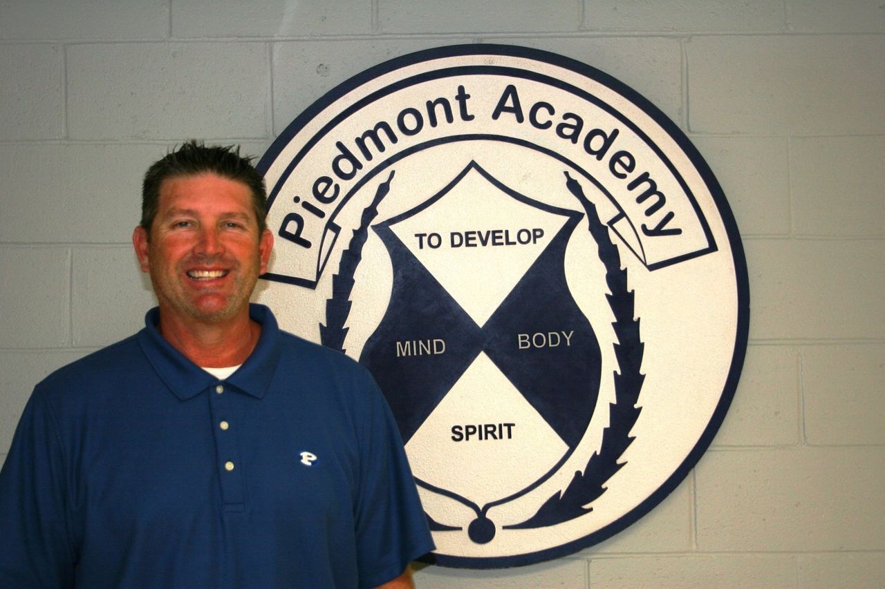 A man stands in front of a sign that says piedmont academy