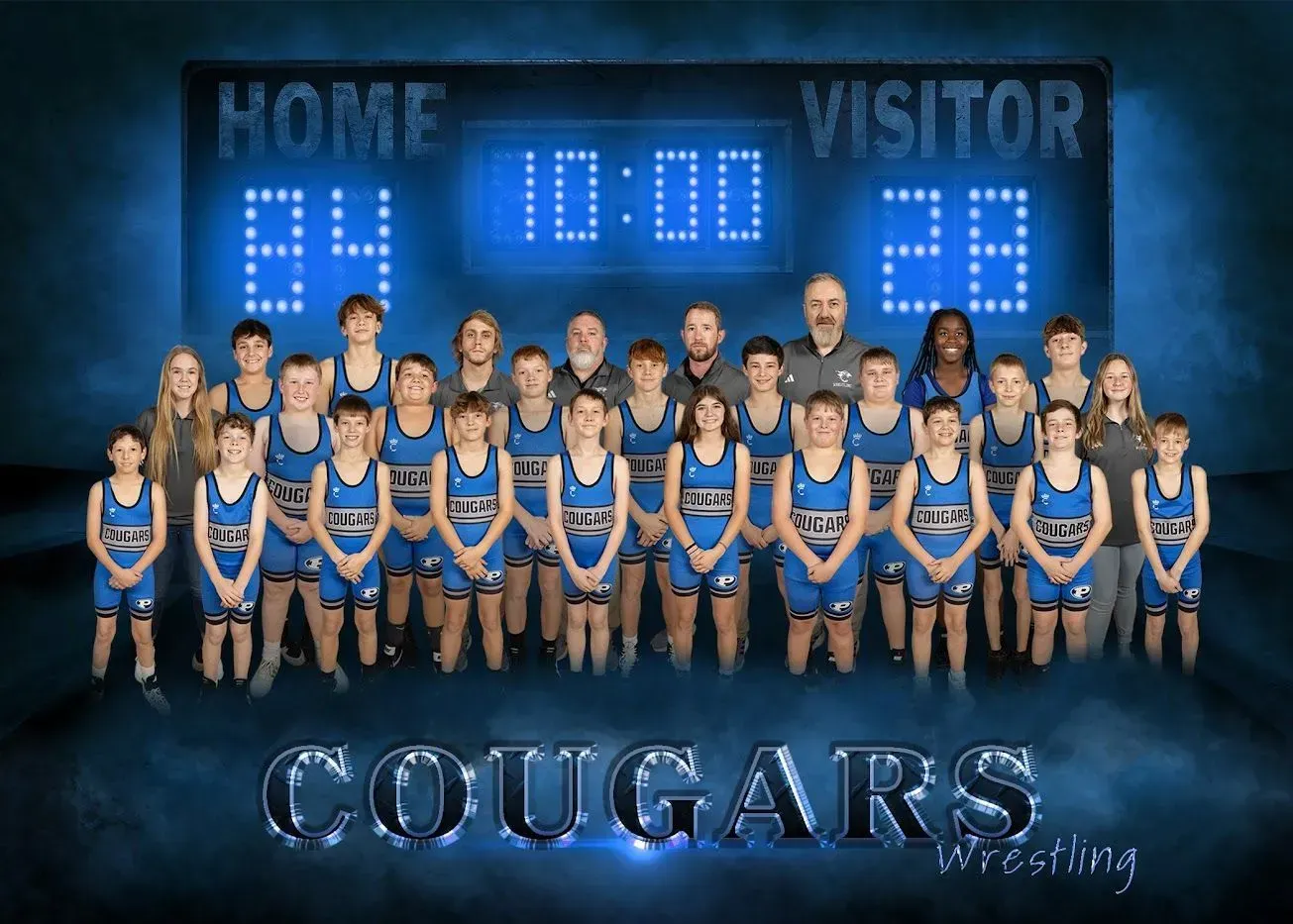 The cougars wrestling team is posing for a picture in front of a scoreboard.