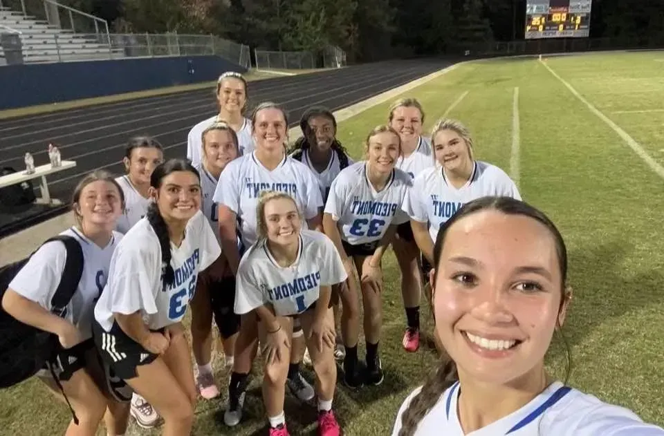 A group of young women are posing for a picture on a soccer field.