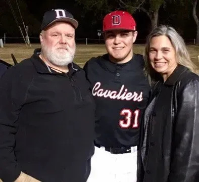 A man wearing a cavaliers jersey is posing for a picture with his parents.