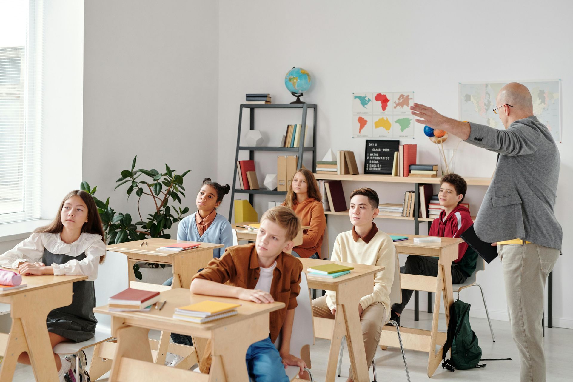 A teacher is giving a presentation to a group of students in a classroom.