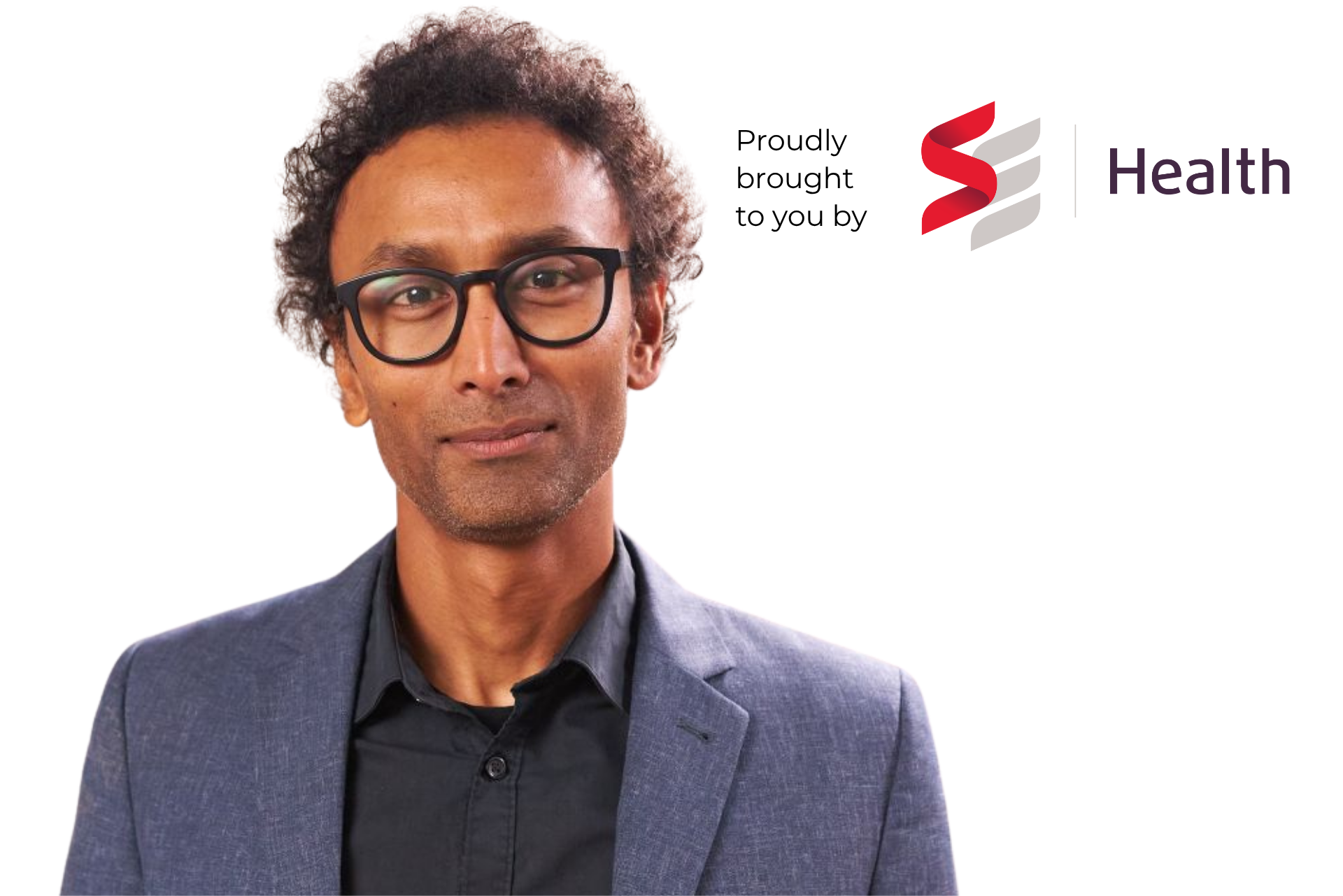 A man wearing glasses and a suit is standing in front of a health logo.