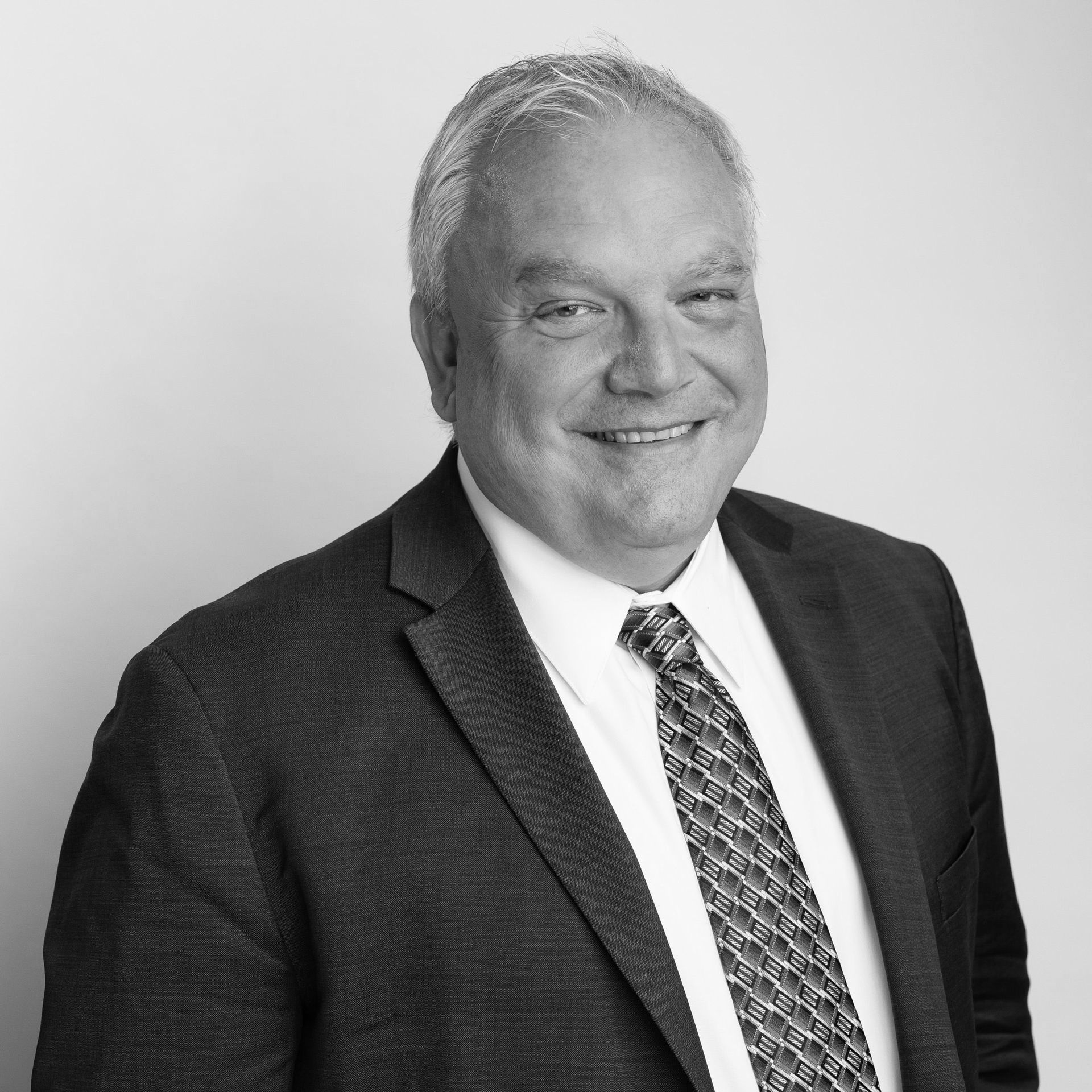 A man in a suit and tie is smiling in a black and white photo.