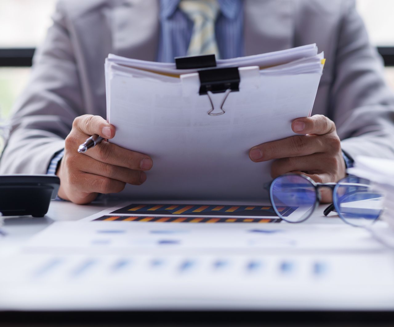 A man is sitting at a desk holding a piece of paper.