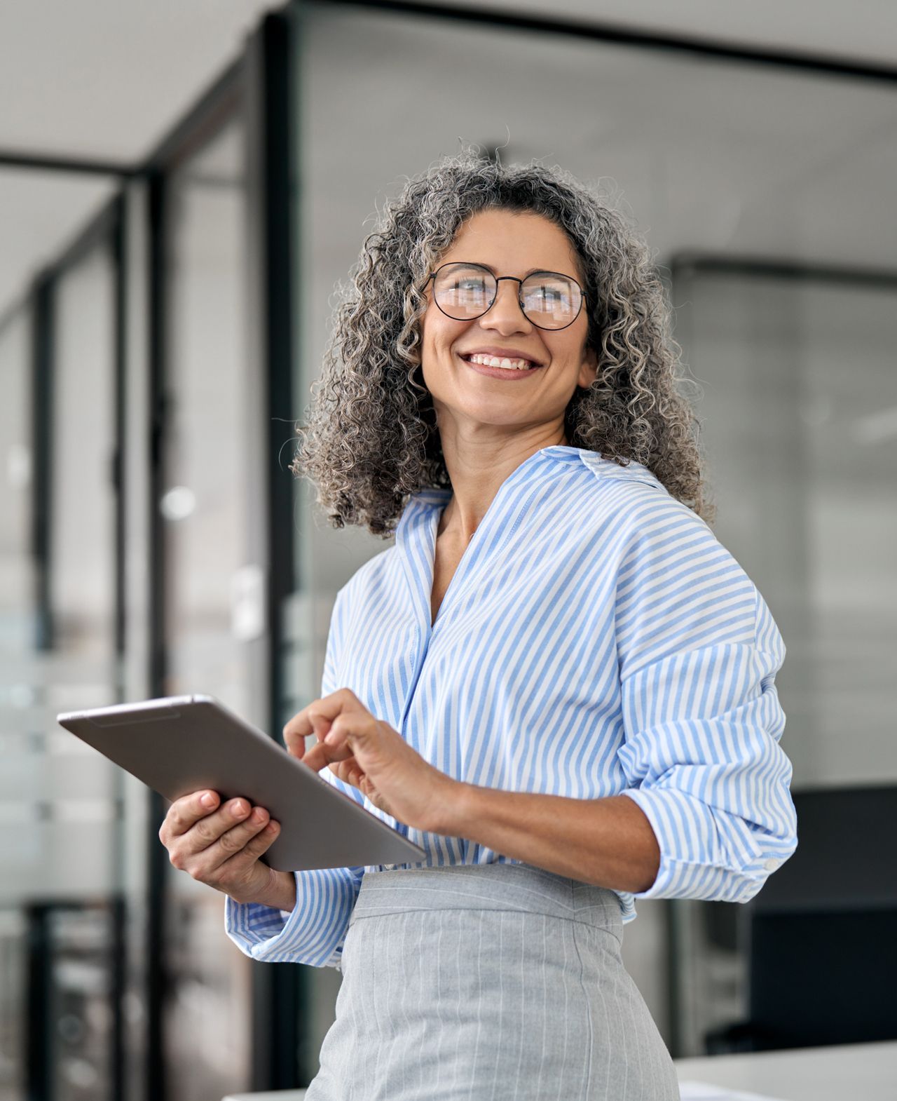 A woman is holding a tablet in her hands and smiling.