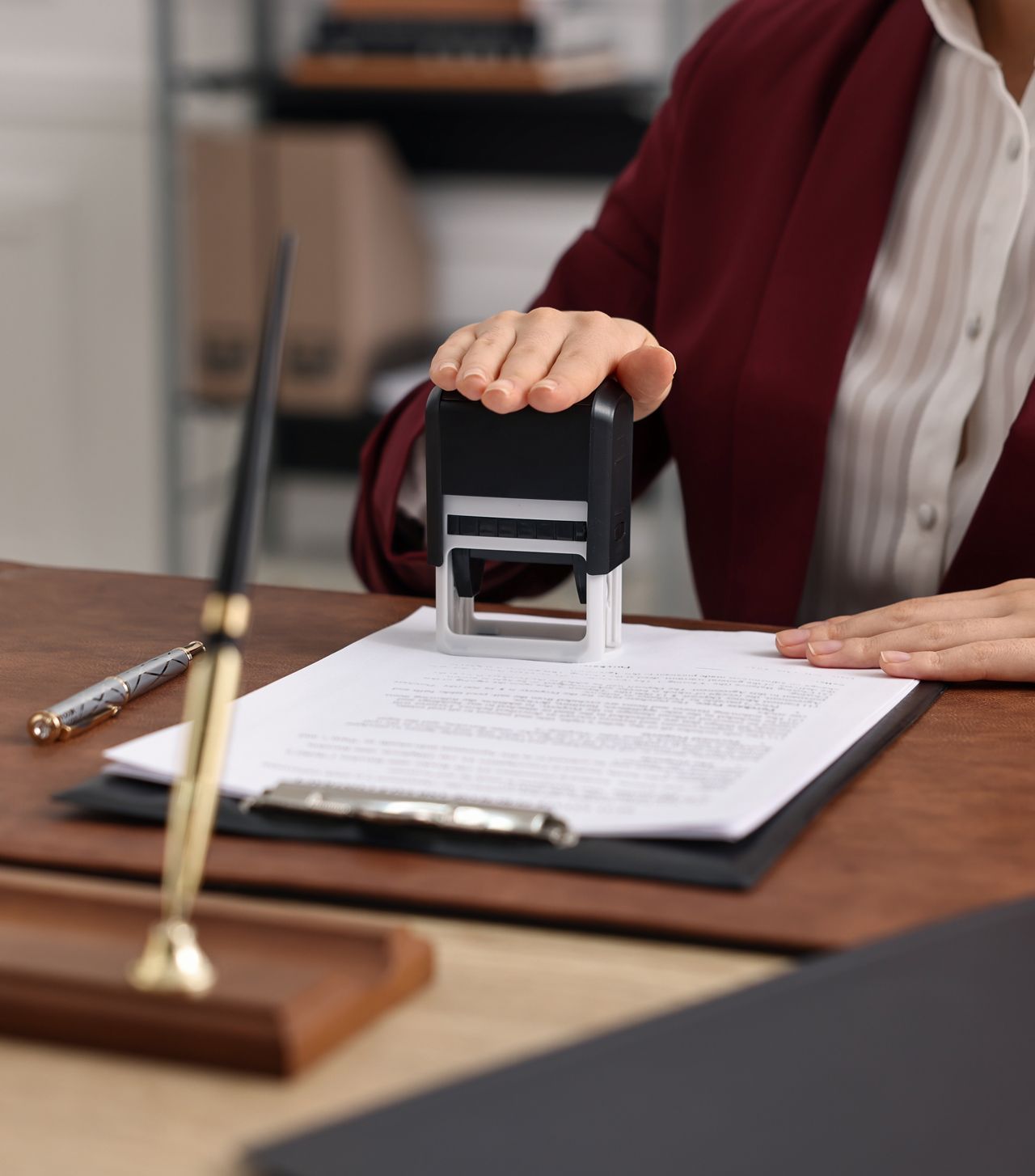 A woman is putting a stamp on a piece of paper