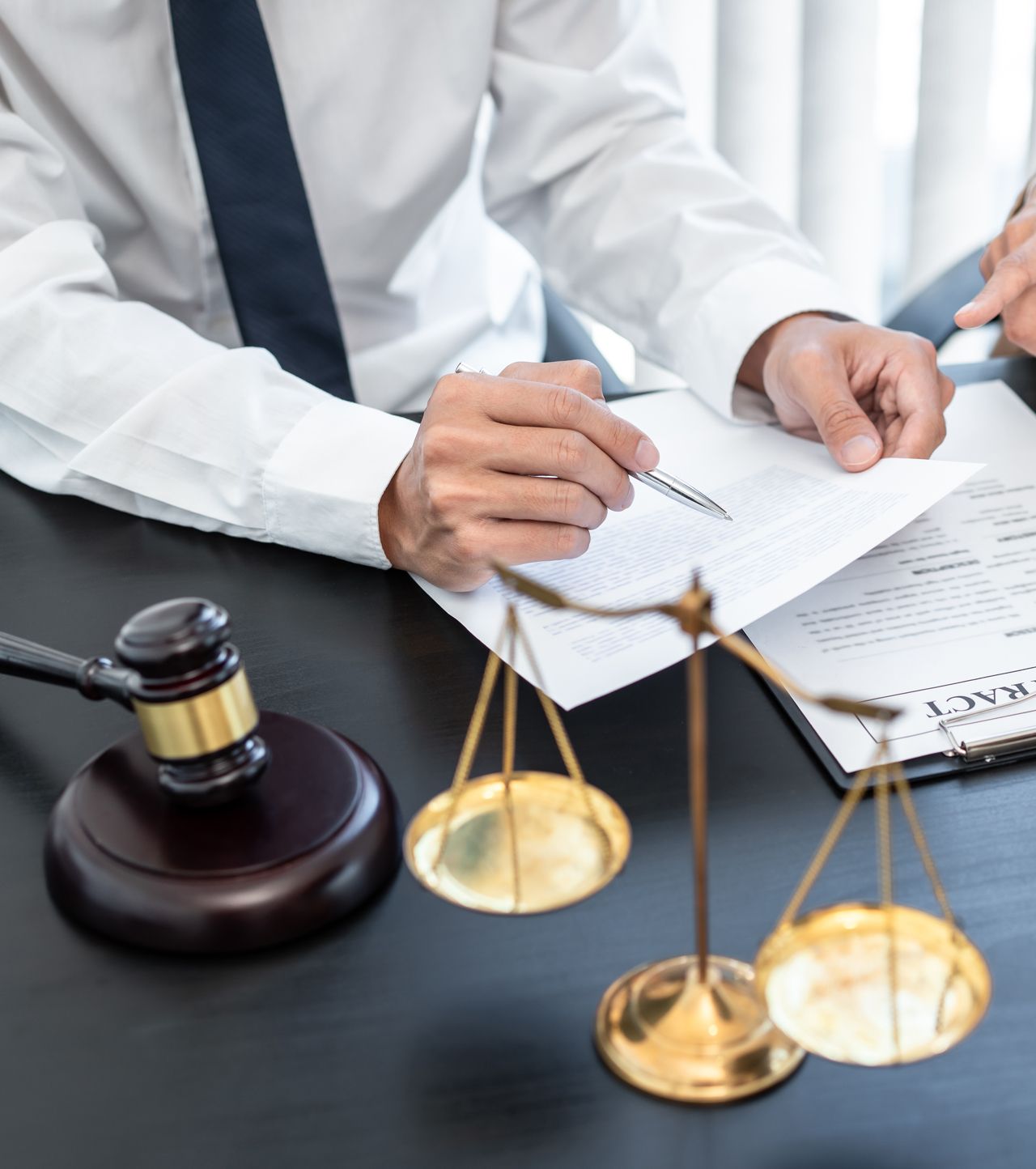 A man is sitting at a desk with a gavel and scales of justice