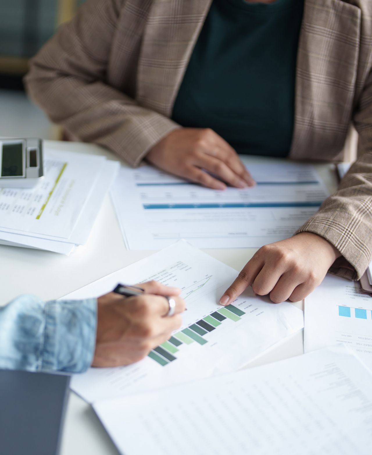 A woman is pointing at a graph on a piece of paper.