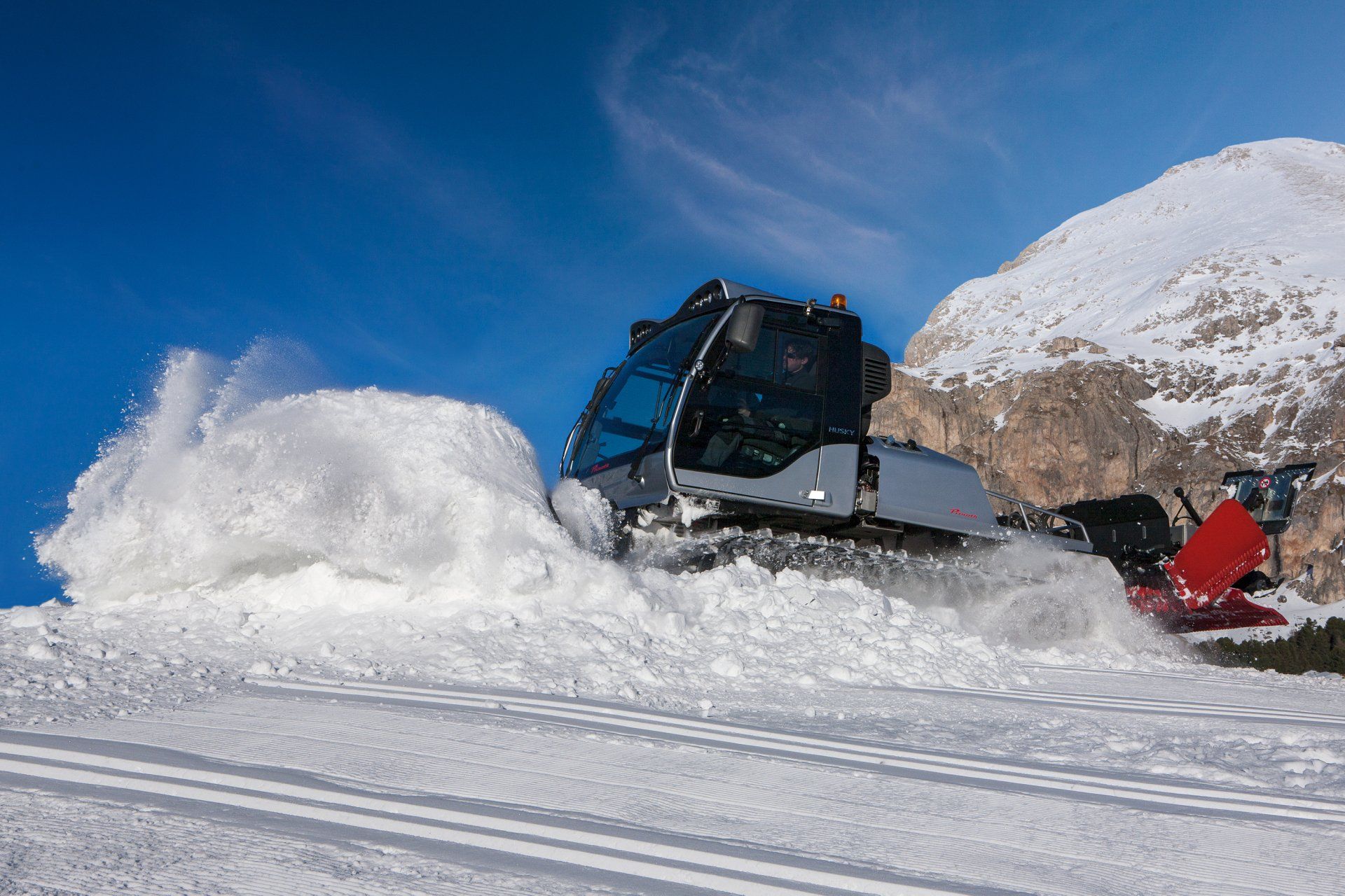 A prinoth Husky plowing the snow on an alpine ski area..