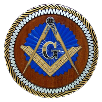 Masonic symbol: blue and gold compass and square over a 'G', on a wooden background with a decorative border.