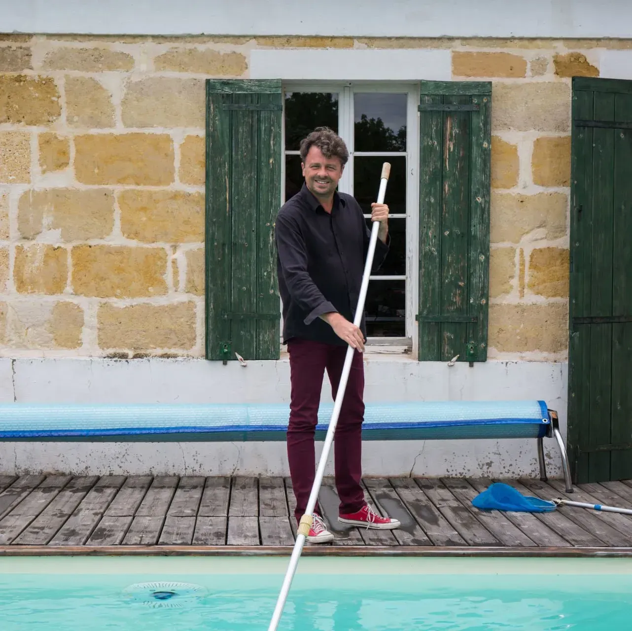A man is cleaning a swimming pool with a mop